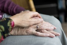 Eine Frau hält ihre Hand über die beiden Hände einer älteren Frau