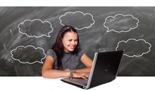 Lachende Schülerin sitzt vor einem Laptop