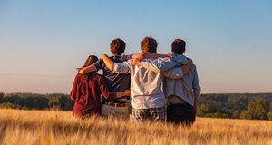 Vier Jugendliche stehen in einem Kornfeld