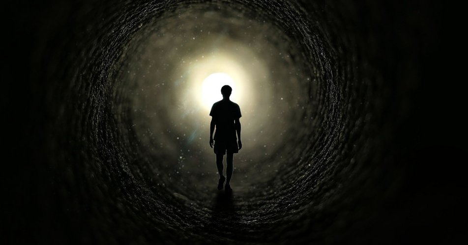 Ein Mensch geht durch ein Tunnel auf ein helles Licht zu