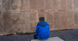 Ein Mann sitzt vor einem Mahnmal für die Opfer des Nationalsozialismus