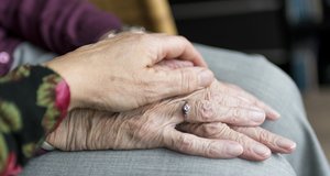 Eine Frau hält ihre Hand über die beiden Hände einer älteren Frau