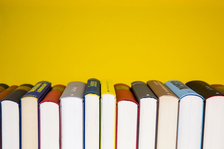 Eine Reihe Bücher vor gelbem Hintergrund