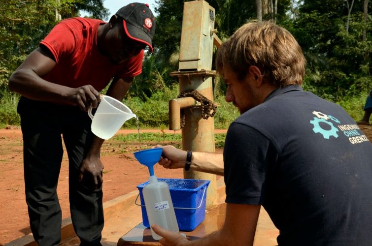 Zwei Menschen schöpfen Wasser an einem Brunnen
